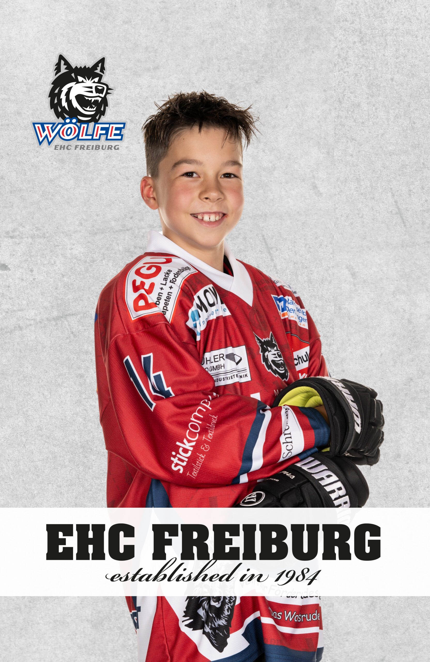 Nachwuchsspieler des EHC Freiburg im Vereinstrikot, Portrait mit Vereinslogo