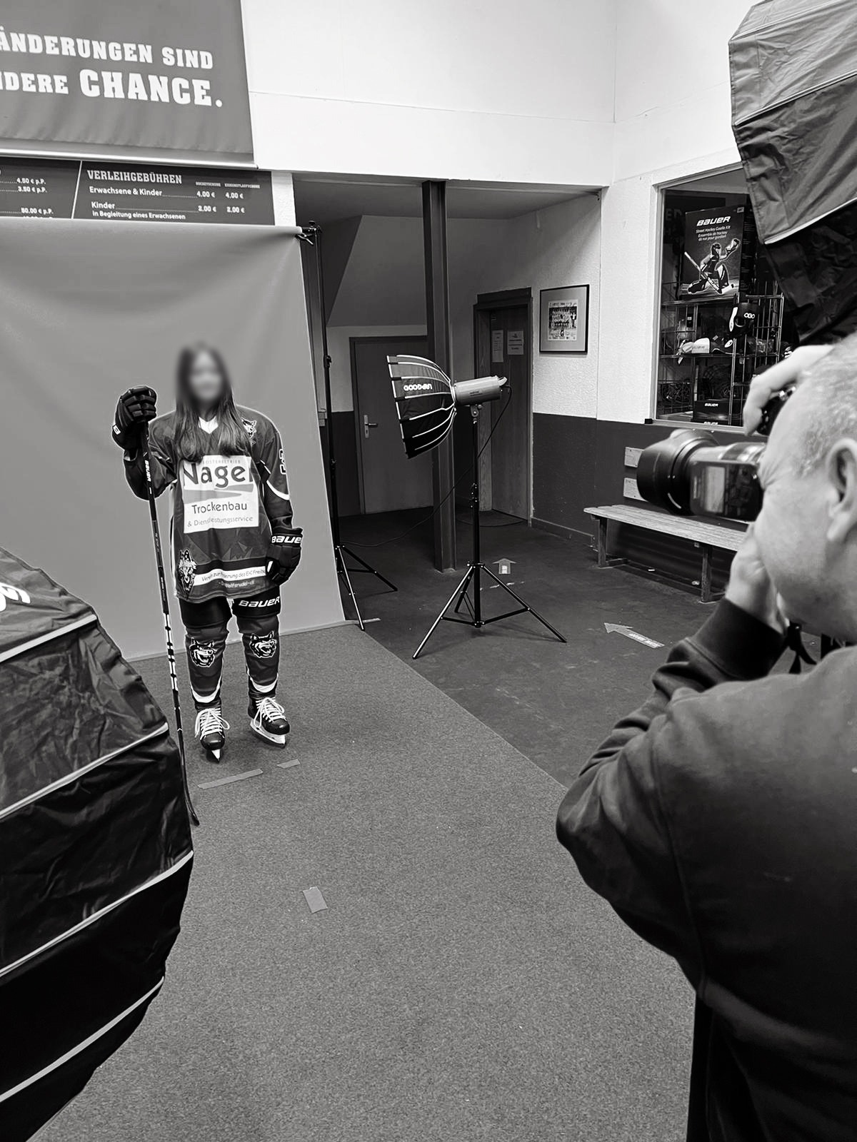 Fotograf fotografiert einen Eishockeyspieler im mobilen Fotostudio in der Eishalle